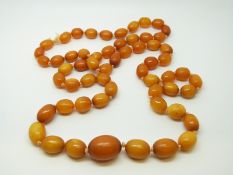 An amber necklace of 59 graduated ovoid egg yolk coloured beads, the largest approximately 18x15mm,