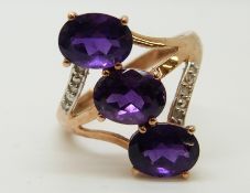 A 9ct gold ring set with three oval amethysts and diamonds (size O)