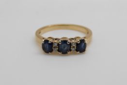 An 18ct gold ring set with three sapphires and diamonds (size M)