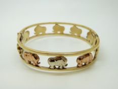 A tri-coloured 9ct gold bangle decorated with elephants, 22.