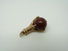 A 9ct gold charm/ pendant in the form of talons gripping a sunstone sphere, 7.
