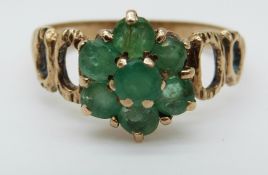 A 9ct gold ring set with an emerald surrounded by diamonds in a cluster (size L)