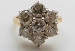 An 18ct gold ring set with seven round brilliant cut diamonds in a cluster,
