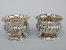 A pair of Victorian hallmarked silver pedestal salts with wrythen decoration and crimped rims,