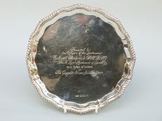 A hallmarked silver salver raised on four ball and claw feet with gadrooned rim,