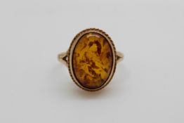 A 9ct gold ring set with pressed amber (size K)