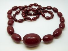 A cherry amber necklace of 49 graduated ovoid beads, the largest approximately 33x24mm, 67g,