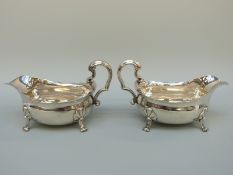 A pair of large Georgian hallmarked silver sauce boats with shaped edges and scrolling handle,