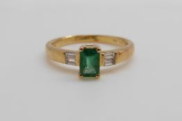 An 18ct gold ring set with an emerald cut emerald of approximately 0.
