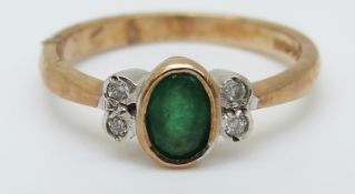 A 9ct gold ring set with an oval emerald and four diamonds (size N)