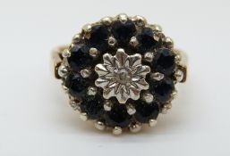 A 9ct gold ring set with a diamond surrounded by sapphires (size J)