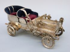 An Indian white metal novelty model veteran car with turning wheels,