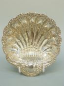 An Edward VII hallmarked silver pierced shell shaped bonbon dish raised on three ball feet,