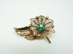 A 9ct gold brooch set with pearls and turquoise in a floral and foliate design
