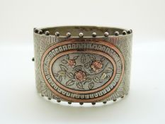 A Victorian silver cuff/ bangle with applied gold foliate and floral decoration