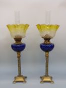 A pair of oil lamps with blue glass reservoirs,