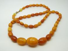 An amber necklace of 52 graduated ovoid egg yolk coloured beads, the largest approximately 20x15mm,