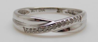 A 9ct white gold ring set with a row of diamonds in a cross over design in original Warren James