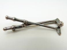 A silver brooch in the form of two golf clubs and ball