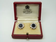 A pair of platinum earrings set with a round cut sapphire measuring approximately 1.
