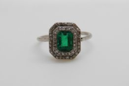 An Art Deco platinum ring set with an emerald cut emerald of approximately 0.