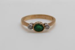 A 9ct gold ring set with an oval emerald and two diamonds (size M)