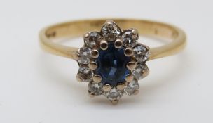 An 18ct gold ring set with an oval sapphire surrounded by diamonds (size P)