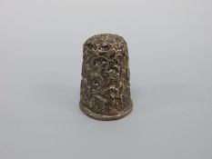 A white metal thimble with embossed floral and foliate decoration,