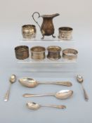 Six various hallmarked napkin rings, five silver spoons and a silver cream jug,