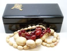 An ivory necklace and a cherry amber necklace in a wooden Chinese box