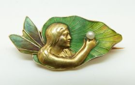 An Art Nouveau 14ct gold brooch depicting a fairy set with green enamel to her wings and holding a