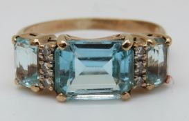 A 9ct gold ring set with three emerald cut topaz and diamonds (size O)
