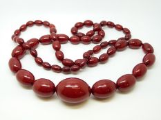 A cherry amber necklace of 63 graduated ovoid beads, the largest approximately 34x24mm, 83g,