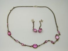 A silver necklace set with pink paste together with matching earrings