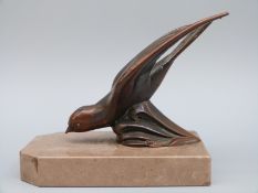 A bronze sculpture or car mascot of a swallow or swift mounted on a marble plinth,