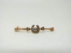 An Edwardian 9ct gold brooch set with seed pearls and a turquoise in a horseshoe design,