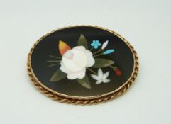 A yellow metal brooch with a rope twist border set with a pietra dura plaque, 4.8 x 3.