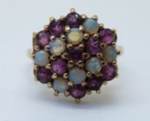 A 9ct gold ring set with rubies and opals in a large cluster (size O)