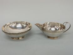 A white metal Arts & Crafts bowl and jug, with hammered decoration and beaded rim,