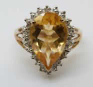 A 9ct gold ring set with a pear cut citrine surrounded by diamonds (size M/N)