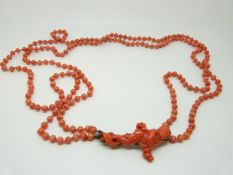 A Victorian two strand coral necklace with a carved coral clasp in the form of a cherub