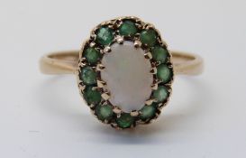A 9ct gold ring set with an opal surrounded by emeralds (size K)