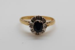 An 18ct gold ring set with a sapphire surrounded by diamonds (size K)