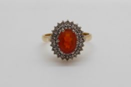 An 18ct gold ring set with a fire opal surrounded by diamonds (size J)