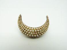 A Victorian brooch/ pendant in a crescent shape set with graduated seed pearls,