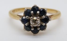 An 18ct gold ring set with a diamond surrounded by sapphires (size K)