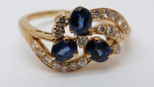 An 18ct gold ring set with three sapphires and diamonds in a floral setting (size R)