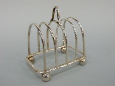 An Edward VII hallmarked silver four division toast rack raised on ball feet, London 1902,