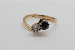 A 9ct gold ring set with a diamond and sapphire in a twist setting (size Q/R)