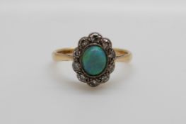 An 18ct gold ring set with a black opal surrounded by old cut diamonds in a platinum setting (size